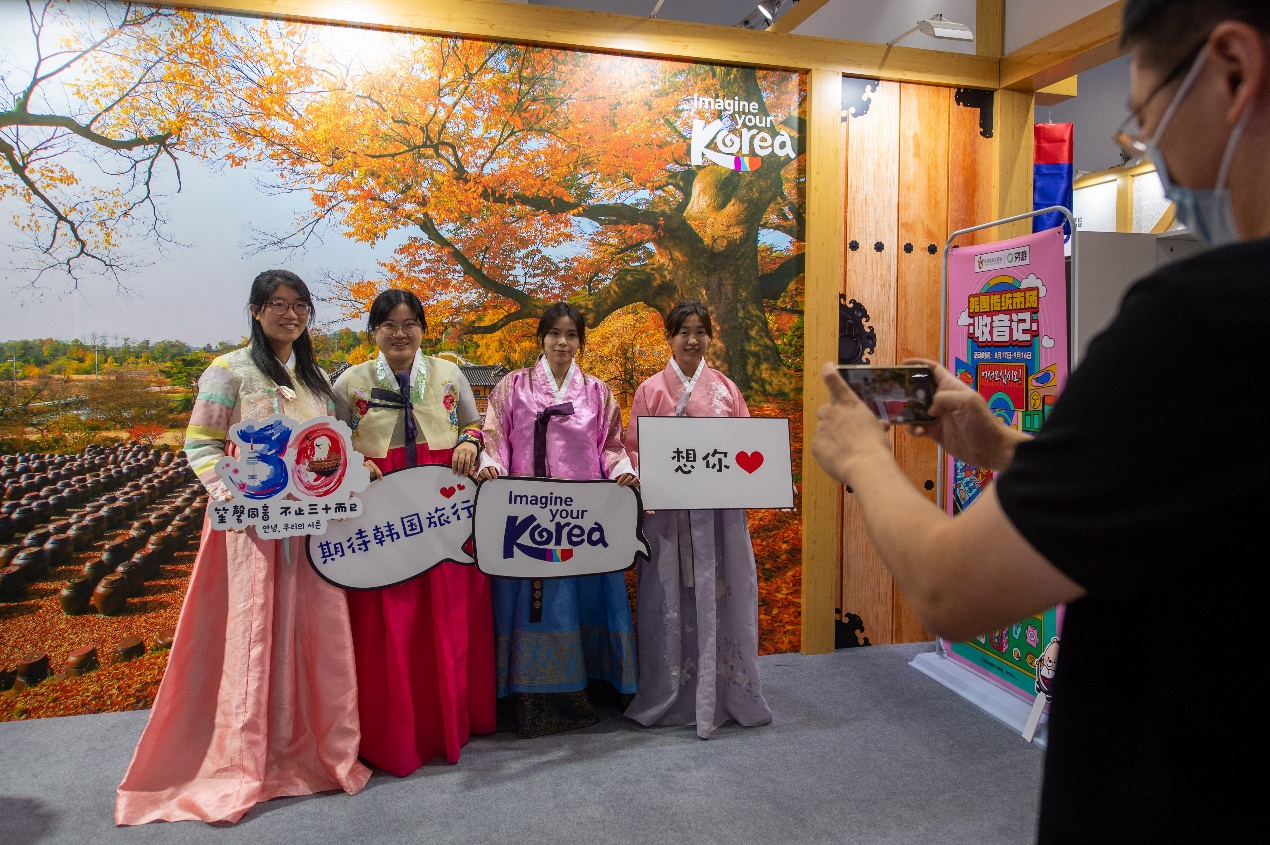 在国家会议中心综合展区的韩国展台，参观者身着韩服合影。人民网记者 翁奇羽摄