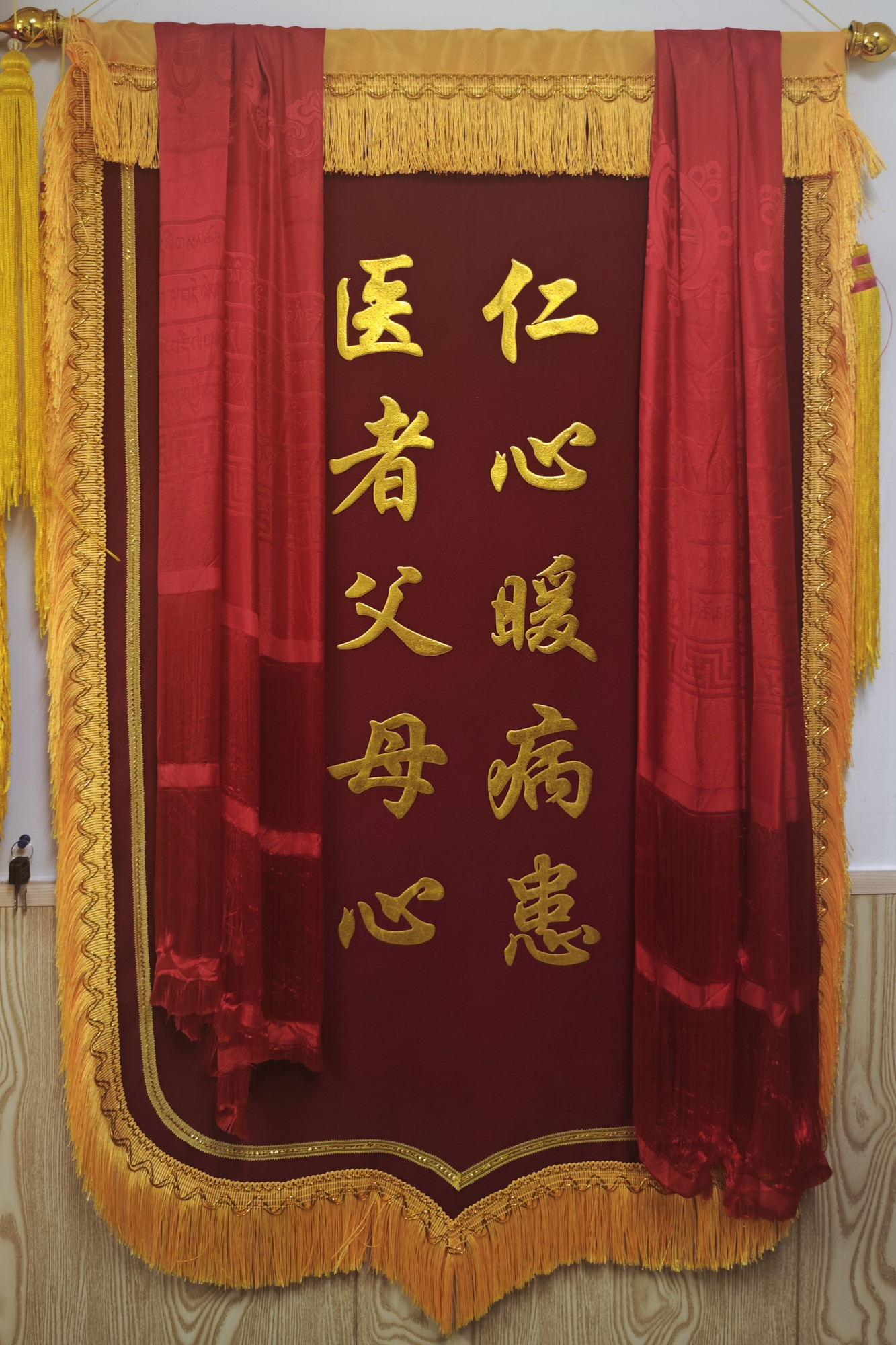 诊室里挂着红布的锦旗，题字为仁心暖病患、医者父母心